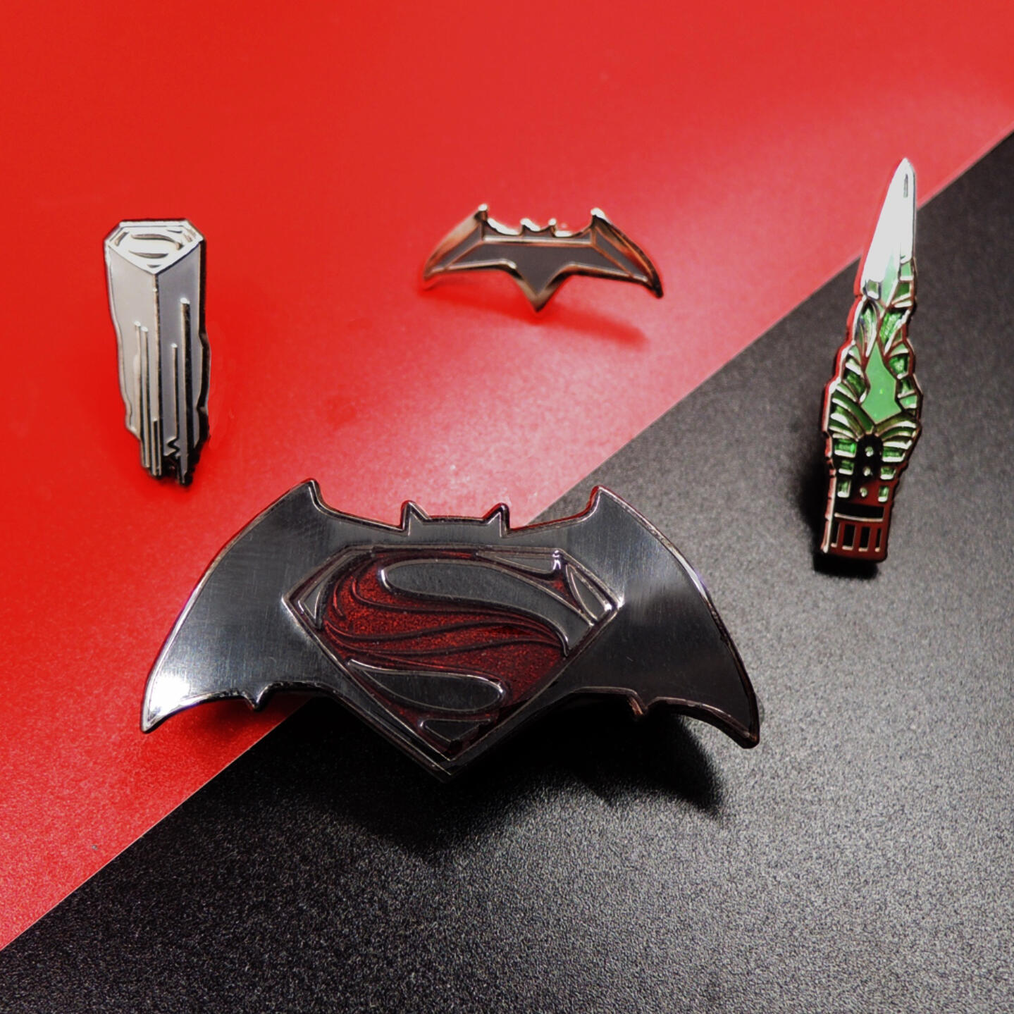 Photo of 4 hard enamel pins: Batman v Superman logo, Kryptonian command key, Batfleck's batarang, and the kryptonite spear